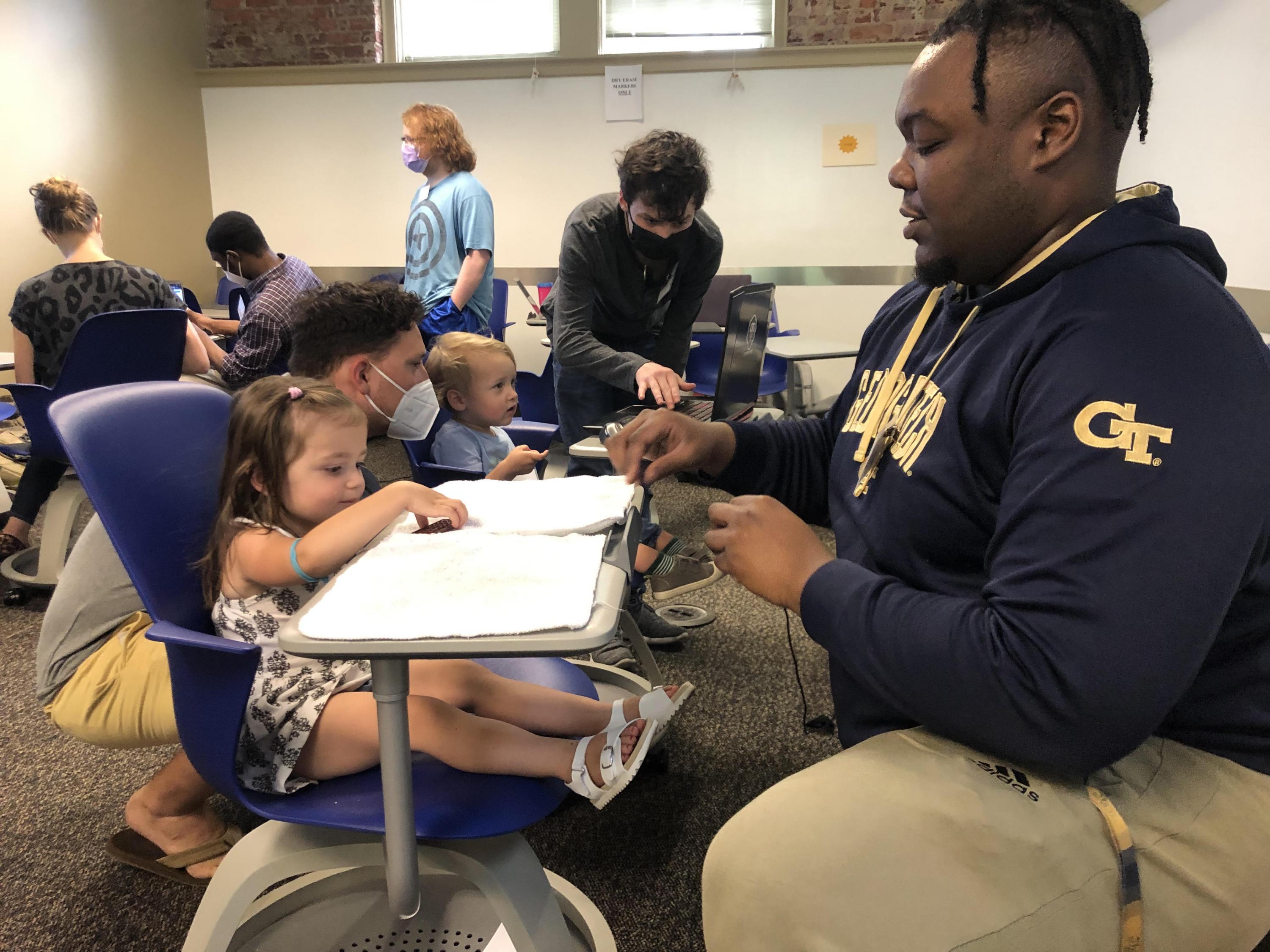 KeAndre Williams (right), a School of Economics major, conducts a test during Child Lab Day June 14. (Photo Christopher Stanzione)